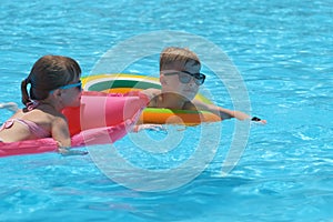 Young child girl relaxing on summer sun swimming on inflatable air mattress in swimming pool during tropical vacations