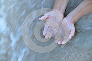 Young child hands in the water flow.