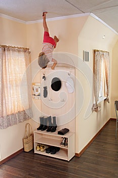 Young child hanging up side down in home