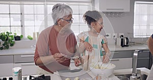 Young child laughing and playing with her grandparents while learning, baking or cooking. A little girl, grandfather and