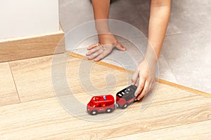 Young child, little girl anonymous kid playing with a small red toy fire truck vehicle, hands pushing a car closeup