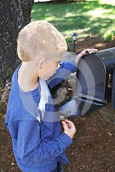 A young child looking in a mailbox.