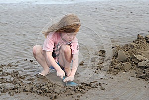 Young child playing, making sandcastles on a beach