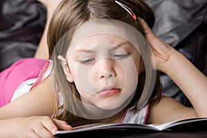 Young Child Reading her Book on the Sofa