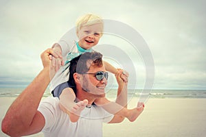 Young Child Riding on Happy Father's Shoulders at Beach