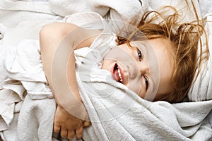 Young child rolling in white covers