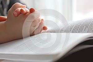 Young Child's Hands Praying on Holy Bible