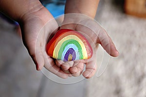 Young Child`s LIttle Hands Holding Painted Rainbow Rock