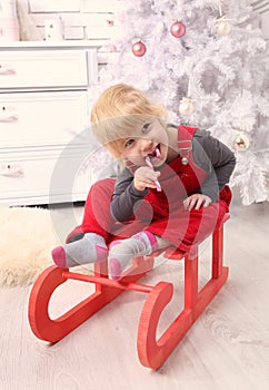 Young child sit indoor on sledge at christmas