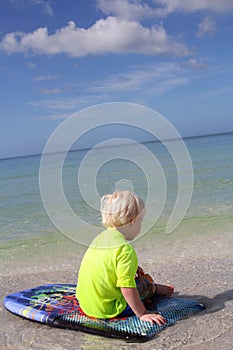 Young Child Sitting on Boogie Board in Ocean
