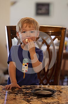 Young child sitting at a table with a marshmallow