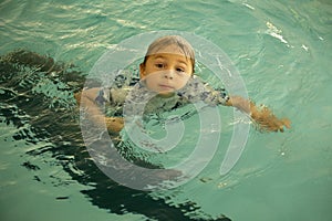 Young child, taking swimming lessons, swimming in clothing, learning how to survive in case of accidental falling into water