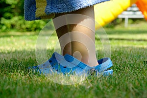 A young child is wearing too big shoes