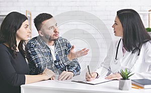 Young childless couple consulting with doctor at clinic