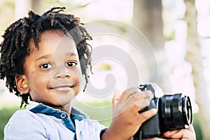 Young children black african skin play with profesisonal photo camera gear in outdoor- playful beautiful child with alternative
