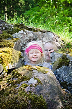Young children, the boy with girl hid among the rocks photo