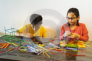 Young children are constructing colorful plastic sticks with glue gun. fun with building geometric figures and learning