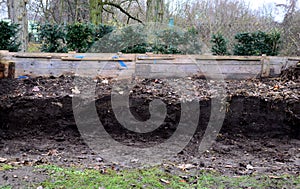 Young children help to distribute soil from compost. They load a dad`s shovel into wheelbarrow to fill the soil. Large decomposed