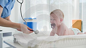 young children pediatrician entertains a small child in a diaper on a diaper table during an examination by a locator in