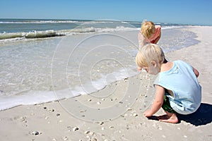 Young Children Picking up Seashell on Beach