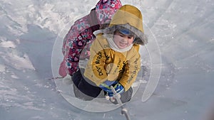 Young children play and have fun on the ice in the winter park. Children pull a rope on the playground of the ice park