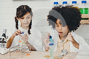 Young children playing exciting with chemistry science kits in school classroom with friend class mate