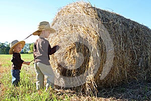 Young Children Playing on Farm with Hay Bale