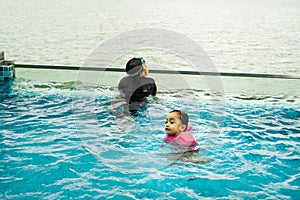 Young children in the pool. Kids having fun in swimming pool.  Wearing goggles on forehead on summer vacation