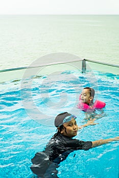 Young children in the pool. Kids having fun in swimming pool.  Wearing goggles on forehead on summer vacation