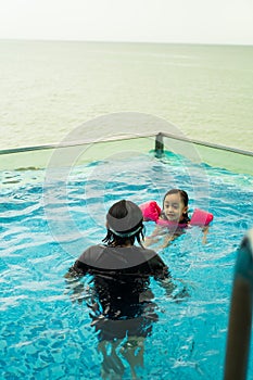 Young children in the pool. Kids having fun in swimming pool.  Wearing goggles on forehead on summer vacation