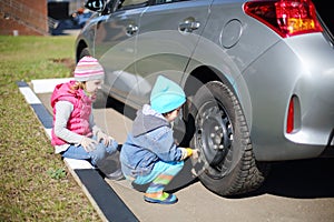 Young children sitting around wheel car with a