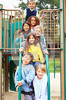 Young Children Sitting On Climbing Frame In Playground