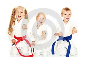 Young children with a smile in kimono sitting in a ritual pose karate punch arm