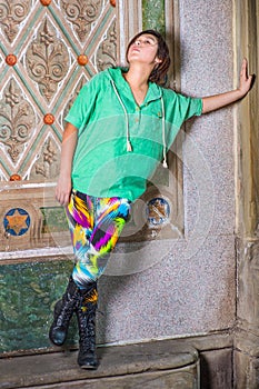 Young Chinese American woman standing against wall in New York City, looking up, thinking