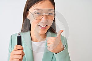 Young chinese businesswoman holding usb memory over isolated white background happy with big smile doing ok sign, thumb up with