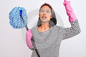 Young chinese cleaner woman wearing gloves holding mop over isolated white background annoyed and frustrated shouting with anger,