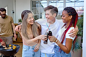 young chinese, european and african friends making toast during barbecue in backyard