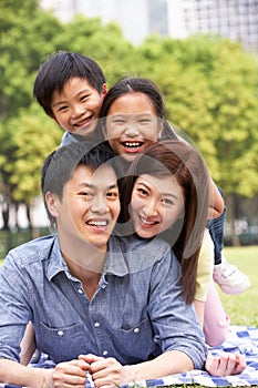 Young Chinese Family Relaxing In Park Together