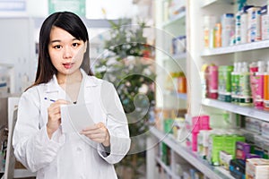 Young Chinese female with notebook in pharmacy