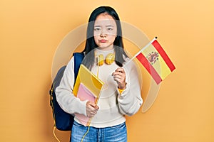Young chinese girl exchange student holding spanish flag depressed and worry for distress, crying angry and afraid
