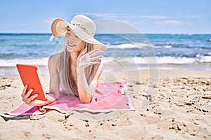 Young chinese girl having video call using touchpad at the beach