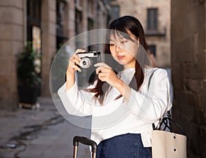 Young chinese girl is taking photos on her camera while journey through the city