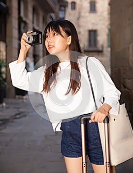 Young chinese girl is taking photos on her camera while journey through the city