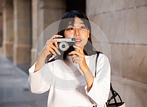 Young chinese girl is taking photos on her camera while journey through the city