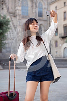 Young chinese girl is taking photos on her camera while journey through the city