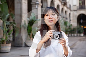 Young chinese girl is taking photos on her camera while journey through the city