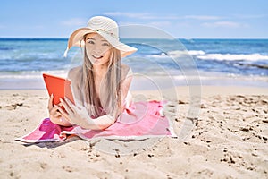 Young chinese girl wearing bikini using touchpad at the beach