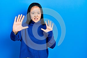 Young chinese girl wearing casual clothes afraid and terrified with fear expression stop gesture with hands, shouting in shock