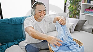 Young chinese guy indulging in music while smilingly doing laundry chores at home photo