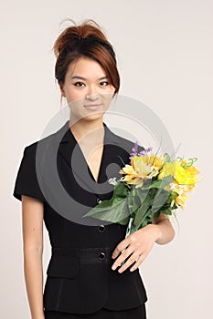 Young Chinese lady in formal attire holding flowers and happy